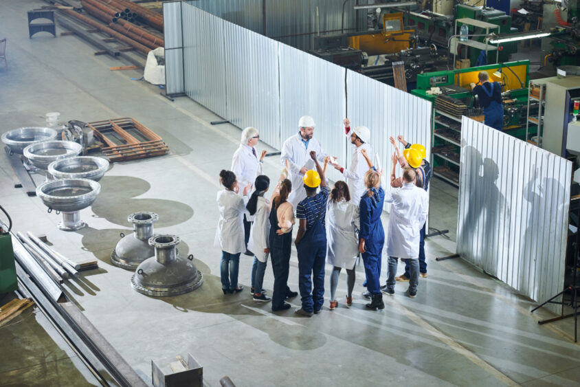 Full length  portrait of mature factory managers talking to group of angry workers during meeting in industrial workshop, copy space